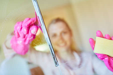 Cleaning lady or domestic help at the window cleaning glass as a serviceの写真素材