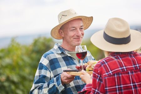 Harvester couple is doing a wine tasting with grapes and red wine