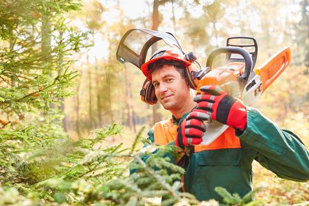 Satisfied forest worker or lumberjack with chainsaw and in protective clothingの写真素材