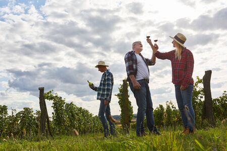 Winegrowers do a wine tasting with red wine in the vineyard