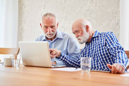 Two seniors surfing the Internet at the laptop computer in the retirement home