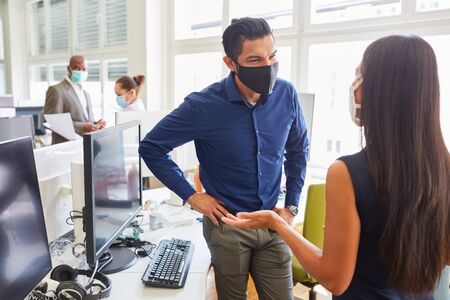 Two business people with face mask because of Covid-19 in a start-up office during a meetingの写真素材