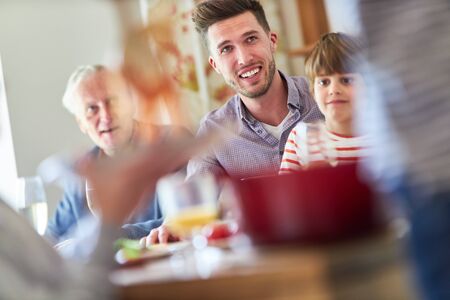 Happy family with children and grandparents having spaghetti mealの写真素材