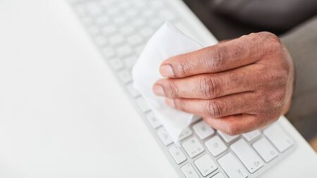 Hand of businessman disinfecting keyboard in office because of Covid-19 and corona virusの写真素材