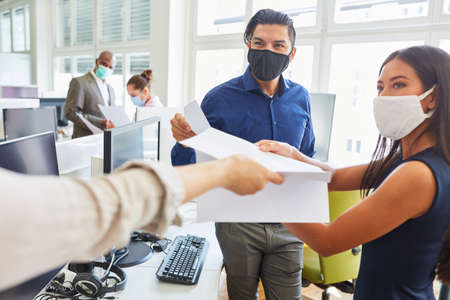 Start-up business people with face mask because of Covid-19 get an important document