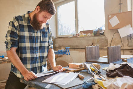 Carpenter with checklist on a piece of paper works order in the carpentry