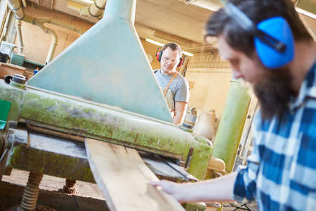 Carpenters or carpenters work with a wood board on the thicknessing machineの写真素材