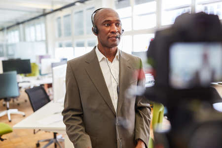 African businessman with headset recording video for an online interview
