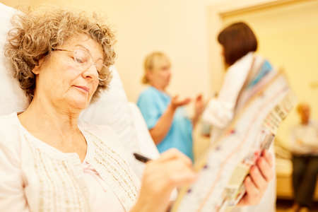 Senior woman as a patient solves puzzles in bed in the hospital or nursing homeの写真素材