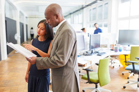 African business man as consultant and Asian colleague discussing a project in the officeの写真素材