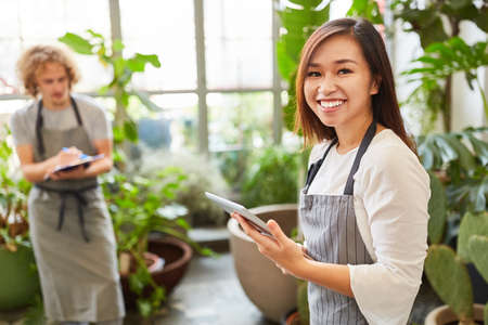 Young florist with tablet computer taking inventory or order onlineの写真素材