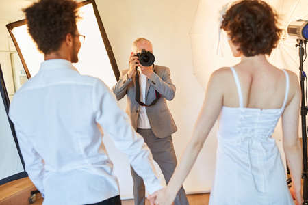 Wedding photographer takes photos of the bride and groom on the wedding day in the photo studioの写真素材