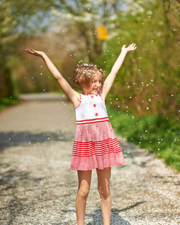 Happy child in spring throws petals in the airの写真素材