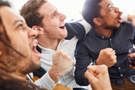 Cheering sports spectators cheer together in a bar or pub at a soccer gameの写真素材