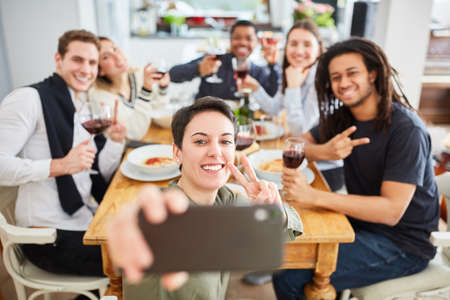 Students take selfie with smartphone while eating at the table of a shared apartmentの写真素材