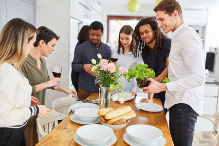 Group of friends in student flat share prepare dining table for meal togetherの写真素材