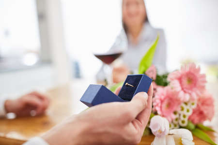 Hand of a man with wedding ring in box on marriage proposal on Valentine's Day
