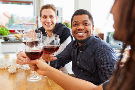 Group of men as friends drinking and clinking glasses of wine in a shared apartment kitchenの写真素材
