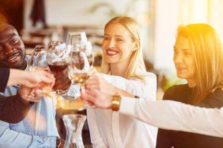 Happy friends celebrate birthday with a glass of wine in the restaurantの写真素材