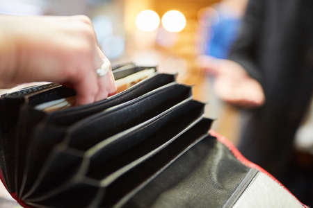 Man looking in the wallet for a bill while paying with cash