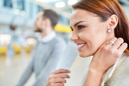 Young woman in the airport terminal or train station looks forward to vacationing with her husband