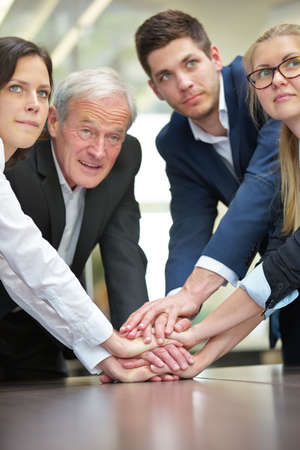 Businesspeople stack hands in the office as a sign of cooperationの写真素材
