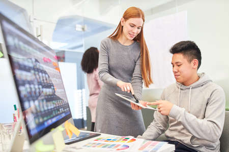 Young woman as web developer together with graphic designer on computer in office