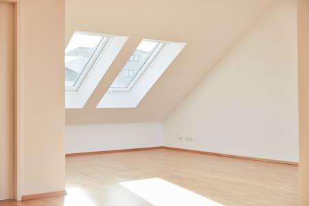 Bright empty room in attic apartment with parquet at home in the day