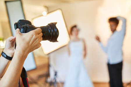 Photographer holds digital camera while preparing for photo shootの写真素材