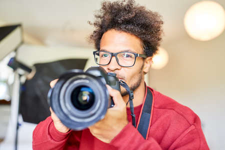 Young man as a creative photographer with reflex camera in studioの写真素材