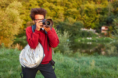 Young man as a landscape photographer with digital camera in the green natureの写真素材