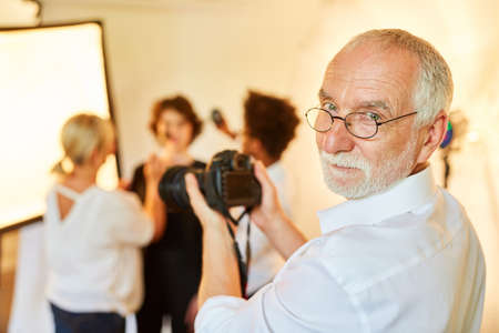 Experienced portrait photographer with camera and team styling for photo shootの写真素材