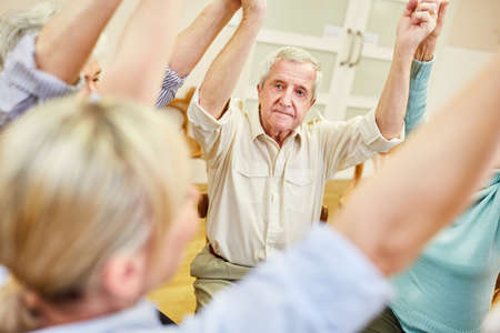 Senior is doing exercise in exercise therapy with other retireesの写真素材