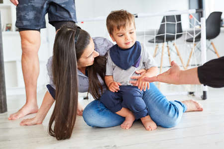 Shy toddler together with mother on the floor in the living roomの写真素材