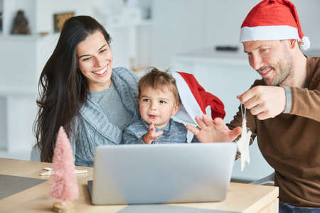 Happy parents having fun with their child video chat at home for Christmasの写真素材