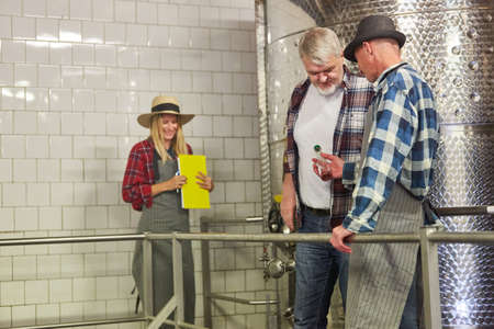 Winemakers and cellar masters discuss a sample of wine in the winery