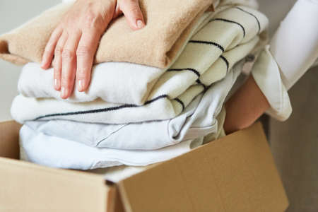Woman packs clothes in a moving box for a clothes donation or for moving