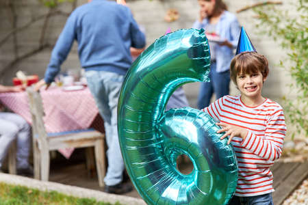 Happy boy celebrates birthday number six in the summer in the gardenの写真素材