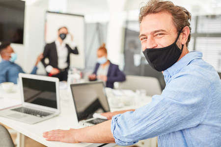 Businessman with everyday mask on laptop computer