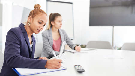 Young business woman is taking notes in a meeting or workshop