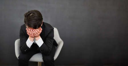 Business woman with hands in front of her face as a sign of crisis and despair