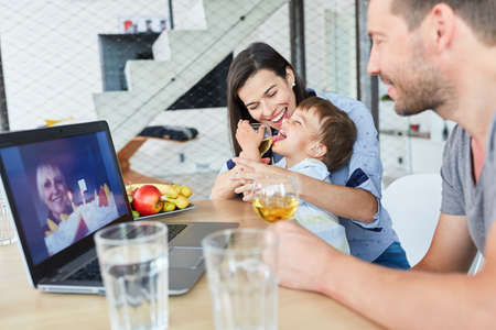 Happy child with parents video chat with grandmother on birthday