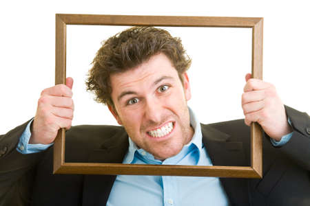 Young man in a suit looks through an empty wooden frameの写真素材
