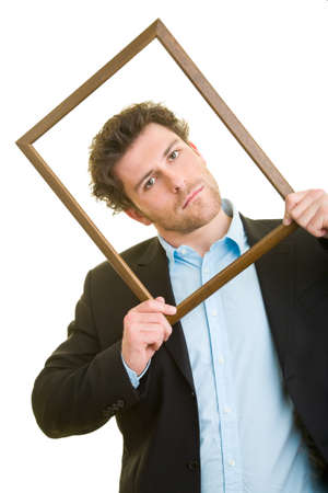 Young man in a suit looks through an empty wooden frameの写真素材