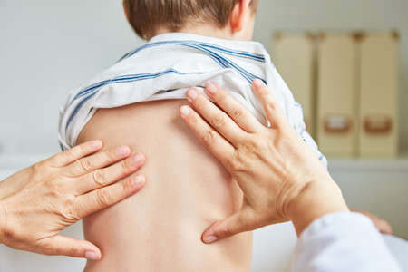 Pediatrician or osteopath treats the back of children during consultation hoursの写真素材