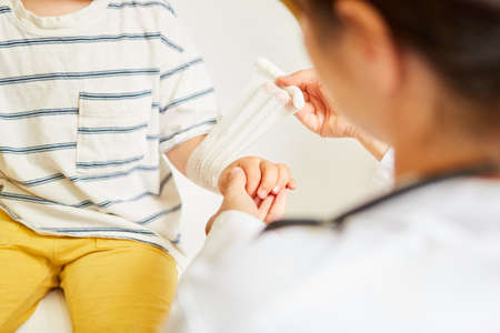 Pediatric ties bandage around child's wrist in case of sprainの写真素材