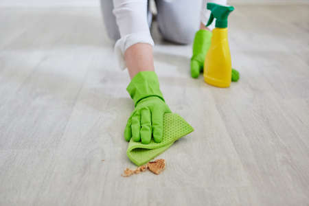 Hands with wiping cloth wipe crumbs from the floor while cleaning the kitchen