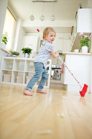 Child sweeping and sweeping with broom at homeの写真素材