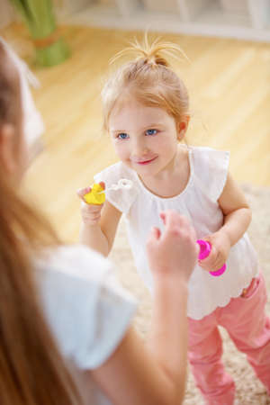 Girl helps her little sister blow soap at home