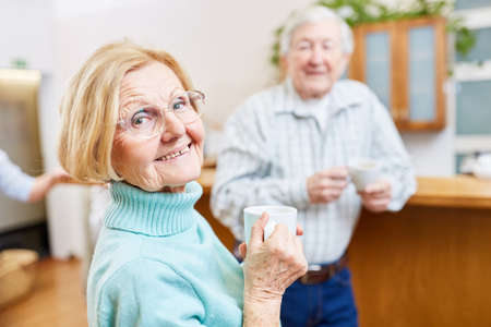 Satisfied seniors with cup of coffee having a small talk in the lounge in the retirement home